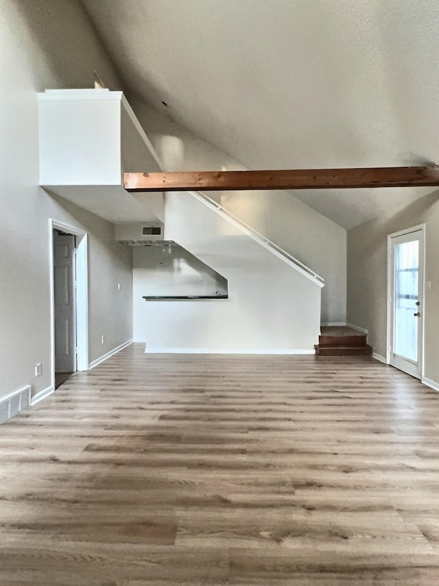 unfurnished living room featuring lofted ceiling and light wood-type flooring