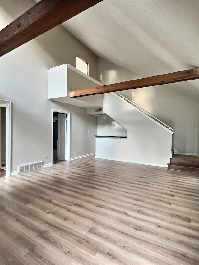 unfurnished living room with light wood-type flooring and a towering ceiling