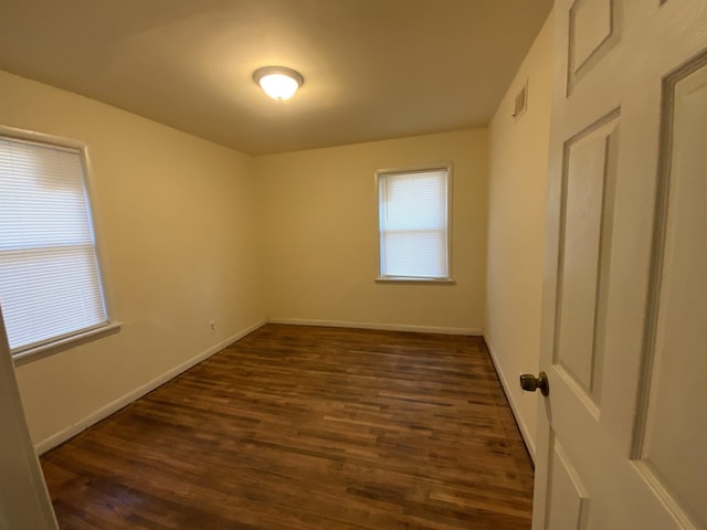 unfurnished room featuring dark wood-type flooring and plenty of natural light