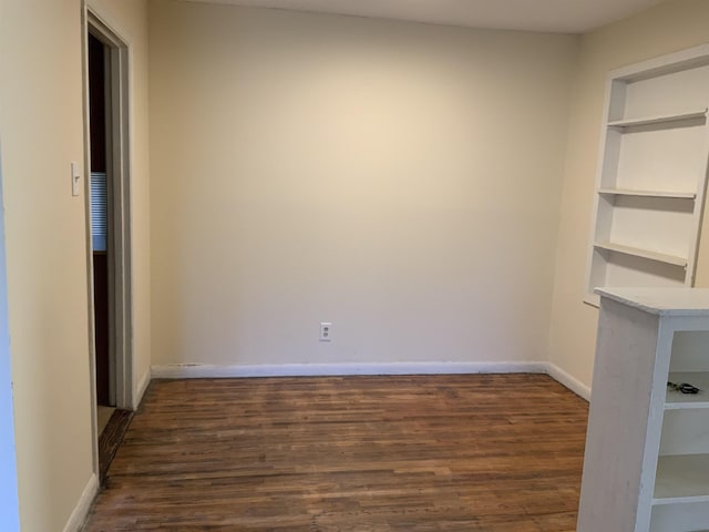 spare room with built in features and dark hardwood / wood-style floors