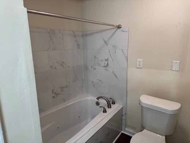 bathroom featuring toilet and tiled shower / bath combo