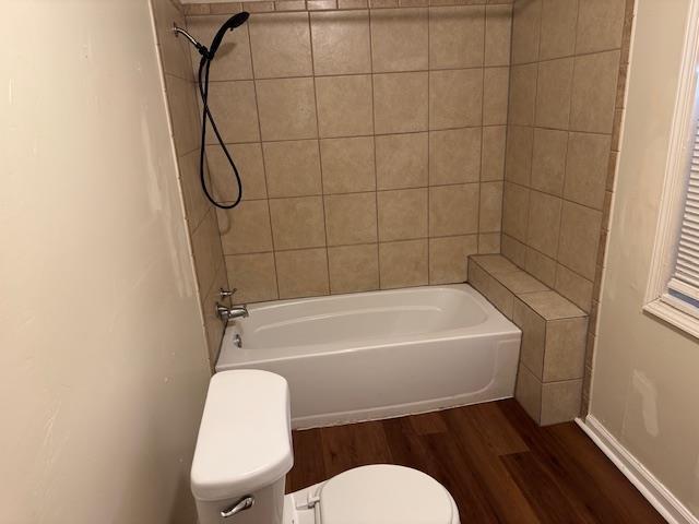 bathroom with toilet, tiled shower / bath combo, and wood-type flooring