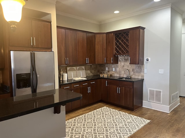 kitchen featuring stainless steel refrigerator with ice dispenser, sink, crown molding, hardwood / wood-style flooring, and dark brown cabinets