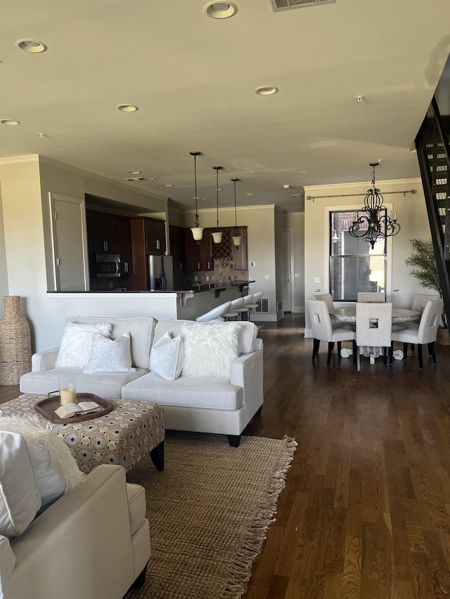 living room featuring crown molding, dark wood-type flooring, and an inviting chandelier