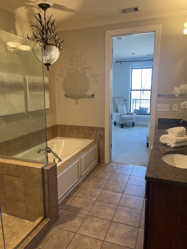 bathroom featuring tiled tub, vanity, crown molding, and tile patterned flooring