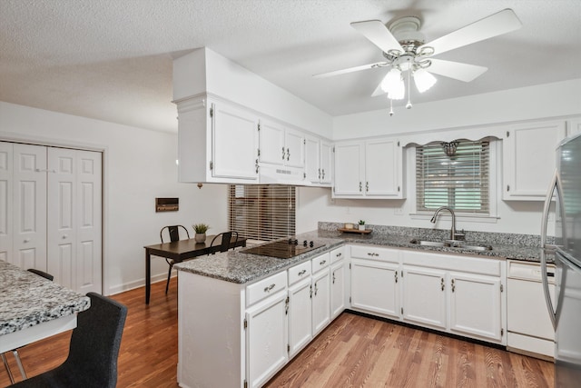 kitchen featuring sink, white cabinetry, kitchen peninsula, and dark stone counters