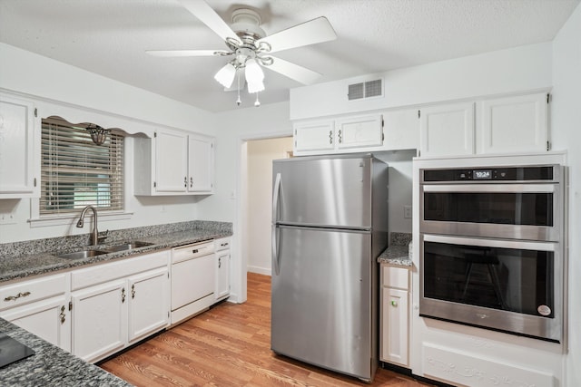 kitchen featuring appliances with stainless steel finishes, sink, white cabinetry, and dark stone counters