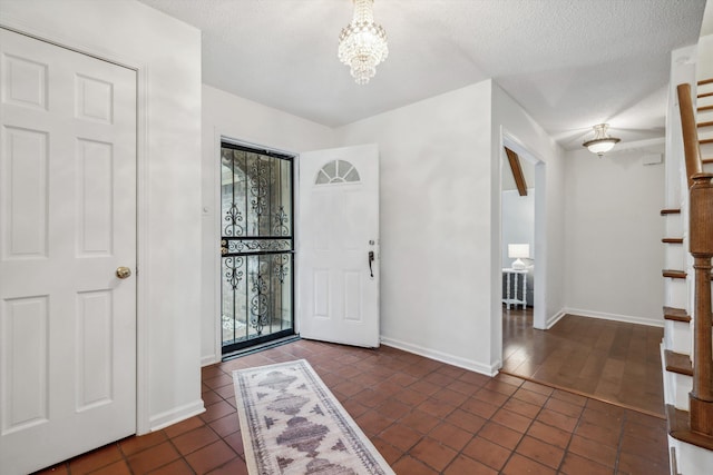 tiled entrance foyer with an inviting chandelier and a textured ceiling