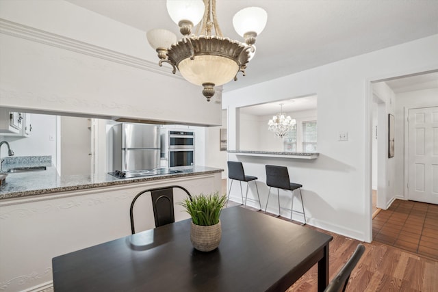 dining area featuring sink, wood-type flooring, and an inviting chandelier