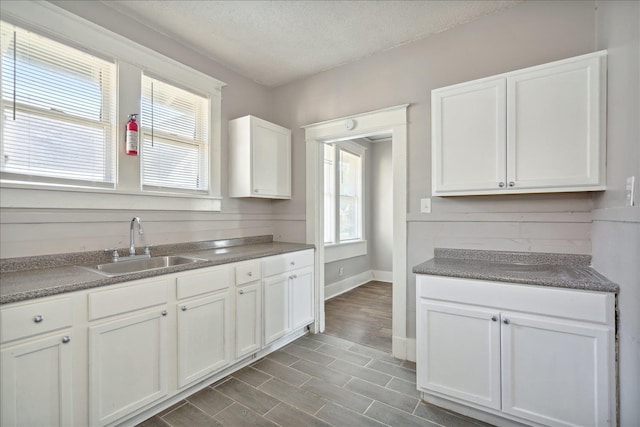 kitchen featuring sink, a textured ceiling, white cabinets, and a wealth of natural light