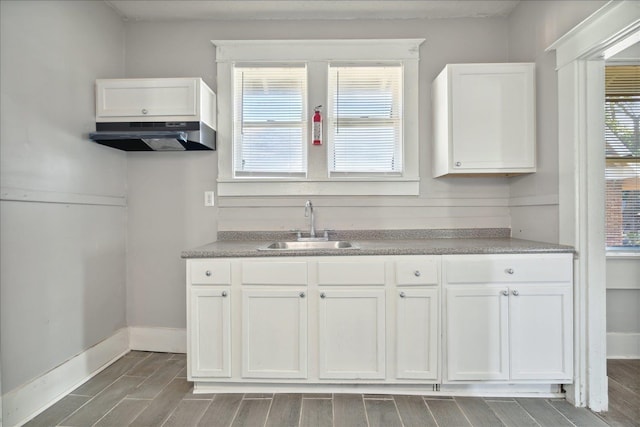 kitchen featuring white cabinets, exhaust hood, and sink