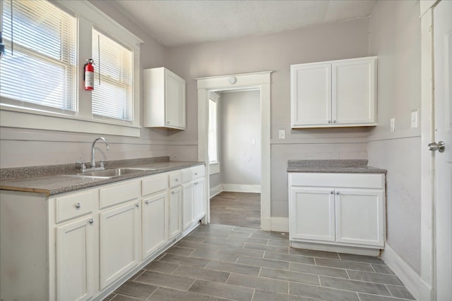 kitchen featuring a textured ceiling, white cabinetry, and sink