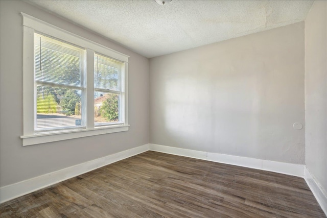 unfurnished room featuring a textured ceiling and dark hardwood / wood-style flooring