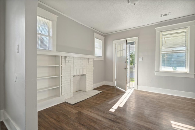 unfurnished living room with a fireplace, dark wood-type flooring, and a healthy amount of sunlight