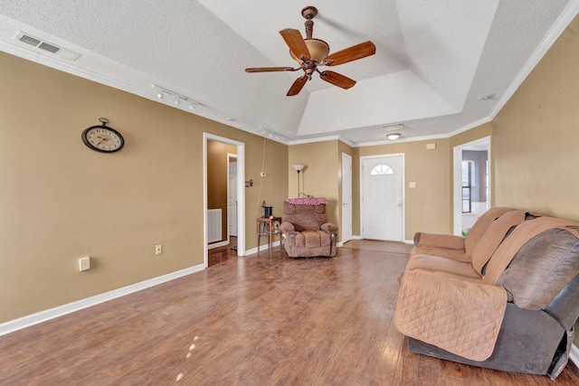 living room with hardwood / wood-style floors, ceiling fan, a raised ceiling, a textured ceiling, and ornamental molding