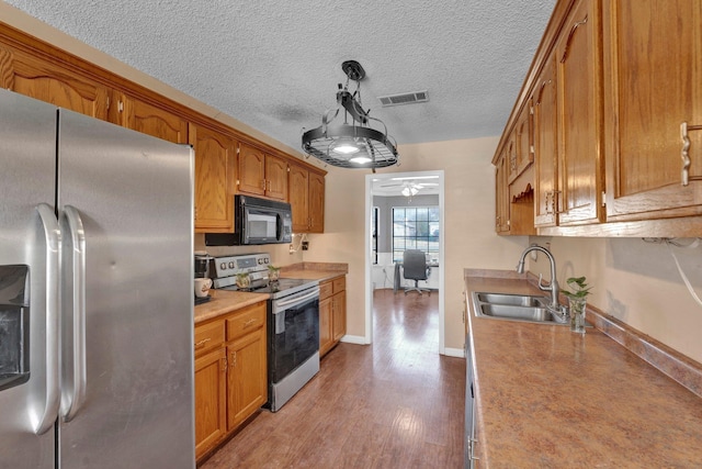 kitchen featuring a textured ceiling, stainless steel appliances, light hardwood / wood-style floors, sink, and ceiling fan