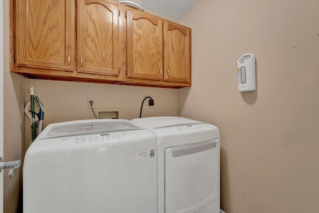 laundry room featuring separate washer and dryer, a textured ceiling, and cabinets