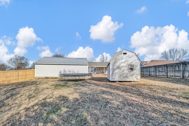 back of property with a yard, a storage shed, and a trampoline