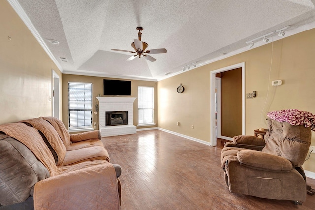 living room with hardwood / wood-style floors, ceiling fan, a tray ceiling, track lighting, and ornamental molding