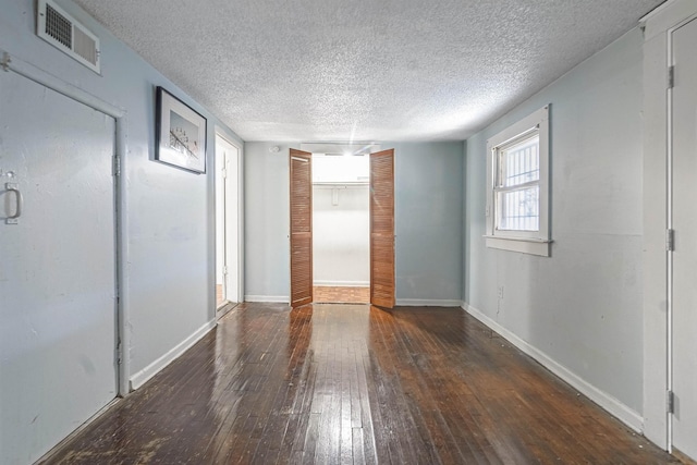 spare room featuring a textured ceiling and dark hardwood / wood-style floors