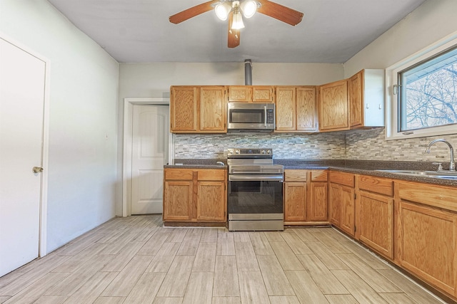 kitchen with decorative backsplash, sink, stainless steel appliances, and ceiling fan