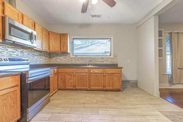 kitchen featuring ceiling fan, appliances with stainless steel finishes, tasteful backsplash, and sink