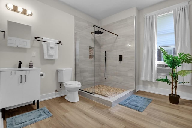 bathroom with toilet, a tile shower, hardwood / wood-style floors, and vanity