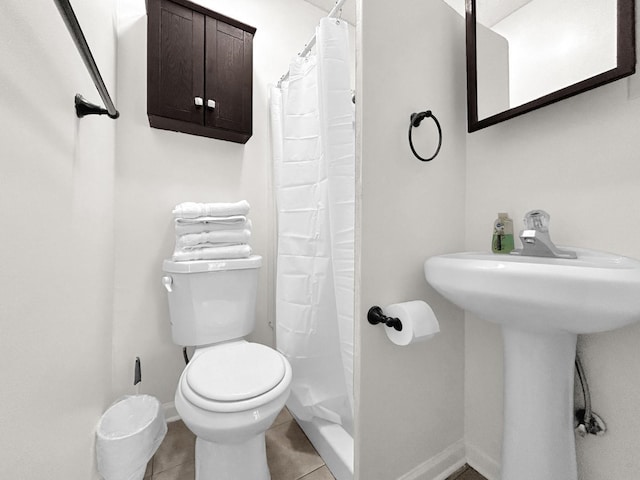 bathroom featuring toilet, tile patterned flooring, sink, and curtained shower