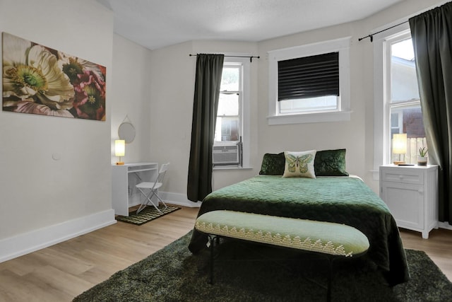 bedroom with light wood-type flooring, multiple windows, and cooling unit