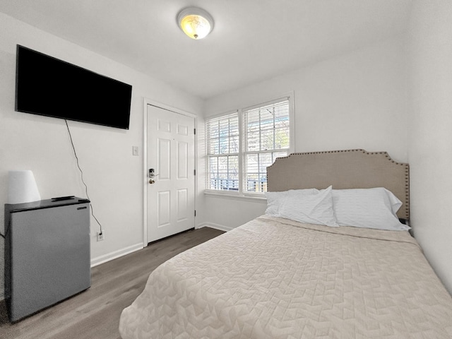 bedroom featuring hardwood / wood-style floors and stainless steel fridge