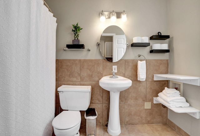 bathroom with toilet, tile walls, and tile patterned floors