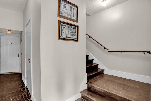 stairs with wood-type flooring and a textured ceiling