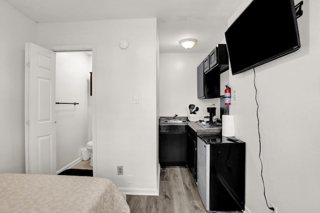 bedroom with light wood-type flooring and connected bathroom