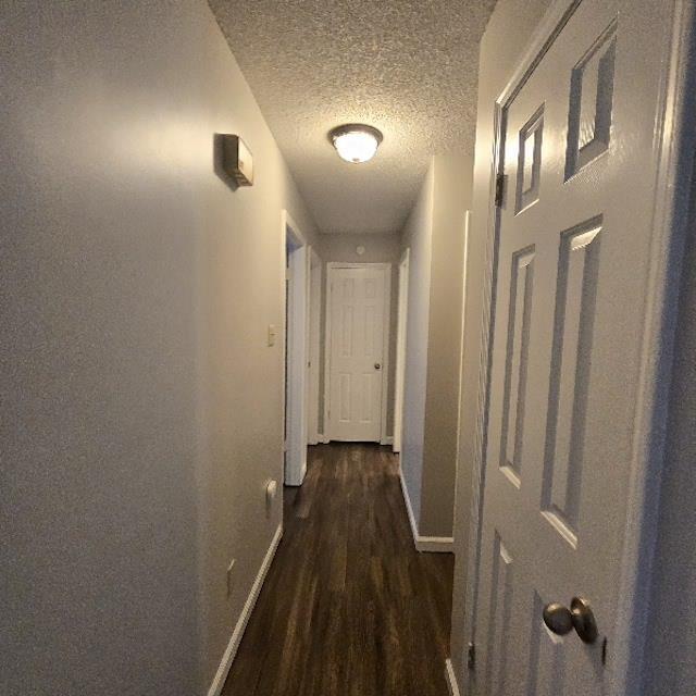 hallway featuring a textured ceiling and dark hardwood / wood-style floors