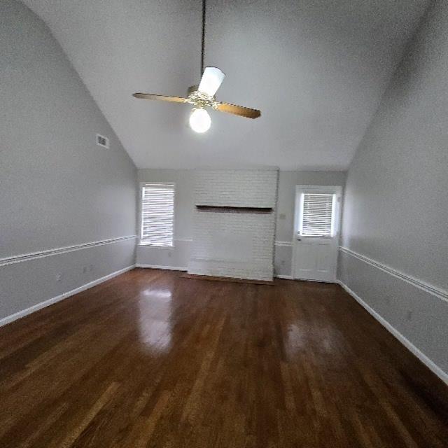 unfurnished living room with dark wood-type flooring, ceiling fan, and lofted ceiling