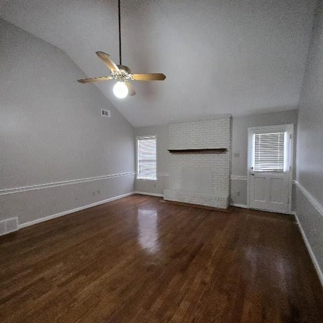 unfurnished living room featuring ceiling fan, vaulted ceiling, dark wood-type flooring, and a fireplace