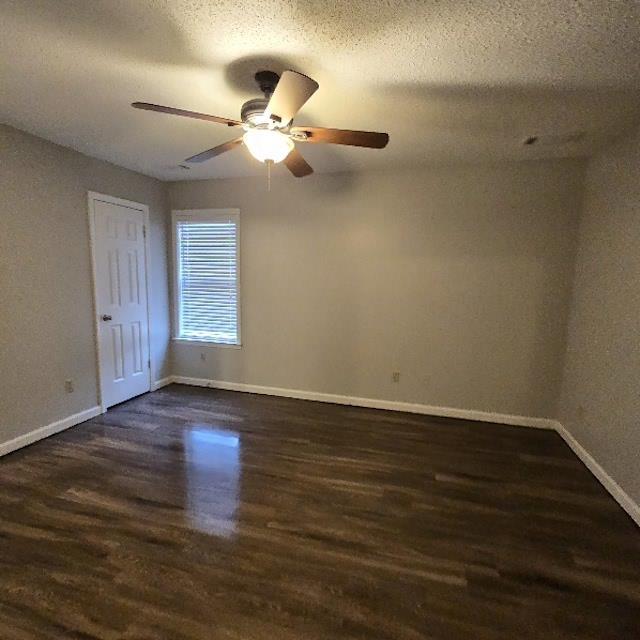 unfurnished room with ceiling fan, dark wood-type flooring, and a textured ceiling