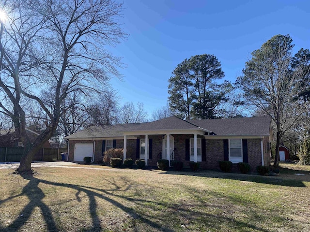 ranch-style home featuring a front lawn, covered porch, and a garage