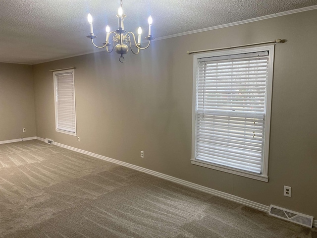 carpeted spare room featuring an inviting chandelier, a textured ceiling, and ornamental molding