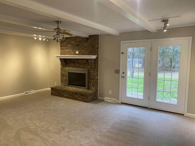 unfurnished living room with a textured ceiling, carpet floors, beamed ceiling, a fireplace, and ceiling fan