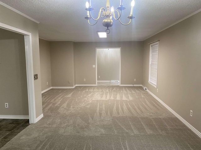 carpeted empty room with a textured ceiling, ornamental molding, and a chandelier