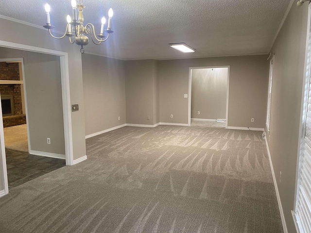 empty room with a textured ceiling, a brick fireplace, carpet, and a notable chandelier