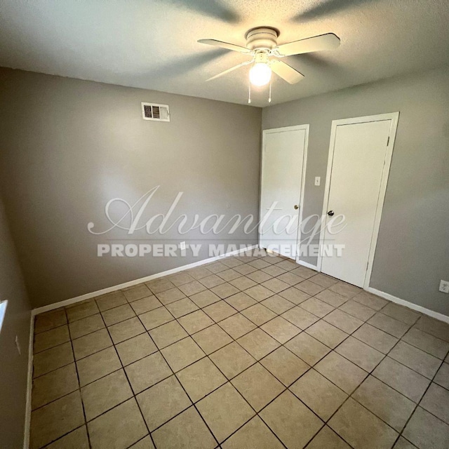 unfurnished room featuring ceiling fan, light tile patterned floors, and a textured ceiling