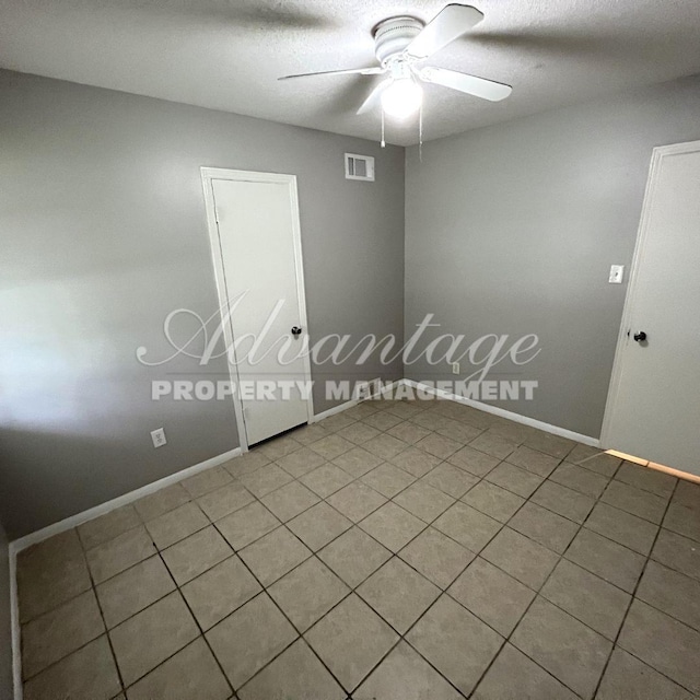 spare room featuring ceiling fan, tile patterned flooring, and a textured ceiling