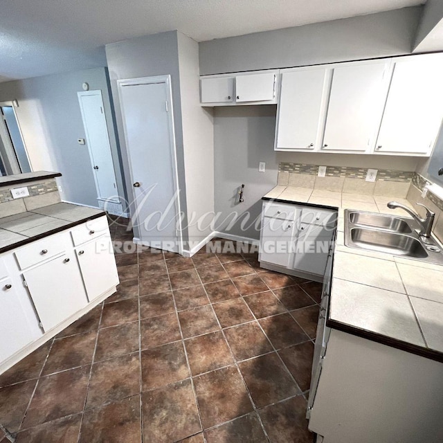 kitchen featuring sink, a textured ceiling, white cabinets, and tile counters