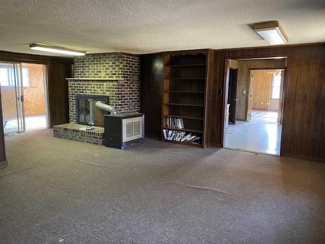 unfurnished living room with carpet floors, plenty of natural light, a textured ceiling, and wooden walls