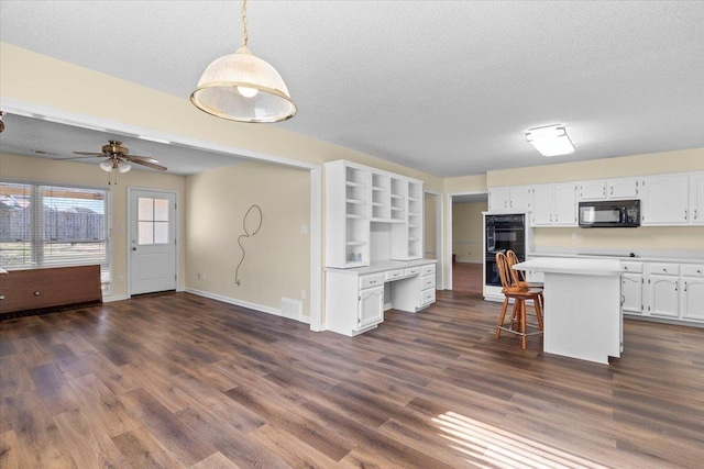 kitchen featuring a kitchen breakfast bar, hanging light fixtures, black appliances, white cabinets, and a center island