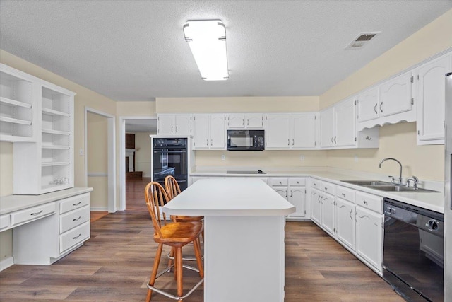 kitchen featuring white cabinetry, a center island, a kitchen breakfast bar, black appliances, and sink