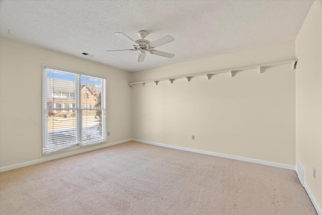 spare room featuring a textured ceiling, ceiling fan, and light colored carpet