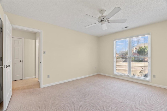 unfurnished room with ceiling fan, light colored carpet, and a textured ceiling